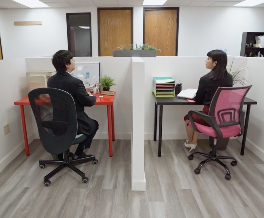 Man and woman sitting and talking by cubicles